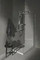 Duschbereich mit transparenter Glasabtrennung, einer Handbrause und einem starren Brausearm. ideal Standard-Produkte, kombiniert mit einem minimalistischen Beistelltisch.